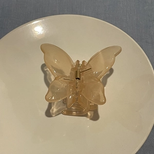 Detail of translucent butterfly hair claw with golden spring on a white ceramic plate