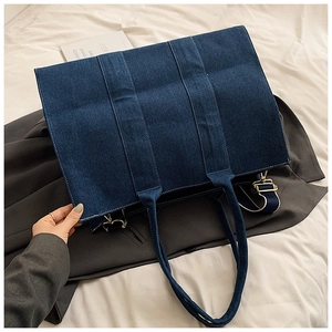 Detailed view of dark blue denim tote bag with contrast stitching and metal hardware
