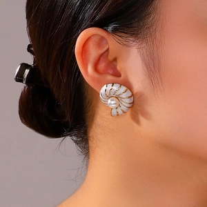 Retro seashell gold earrings with white enamel finish and pearls worn by a model