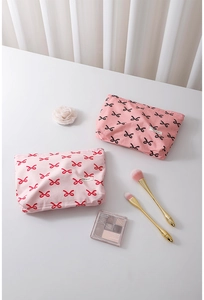 Flat lay of pink cotton makeup bags with bow patterns and gold beauty accessories