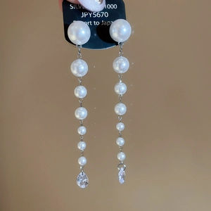 Detail of silver drop earrings with white pearls and a teardrop crystal stone pendant