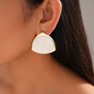 Detail of 14K gold plated triangular earring with white marble texture on ear
