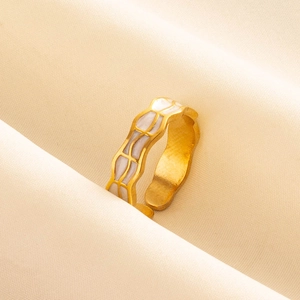 Gros plan d'une bague dorée ajustable avec motifs de vagues en émail blanc sur tissu