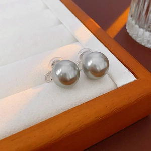 Detailed view of grey pearl ear clip with metal bracket and clear cushion in gift box