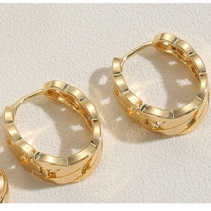 Detail of luxury gold chain-link hoop earrings on a textured minimalist background