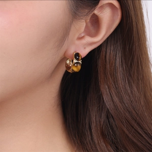 Gold C-shaped stud earrings featuring double tiger eye stones on model ear