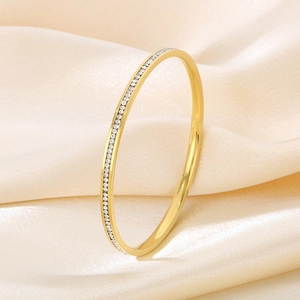 Detail of elegant gold circular bangle with micro-pave white zircon on champagne silk