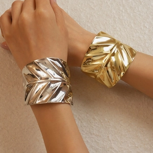 Detailed close-up of metallic cuff bracelets with realistic leaf texture in gold and silver