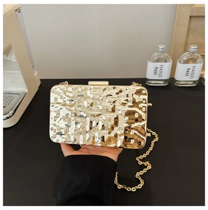 Detail of gold metallic clutch bag with unique pleated texture and detachable chain strap