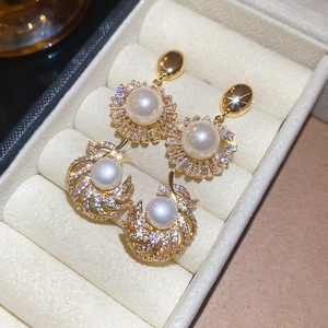 Macro detail of 18k gold plated pearl earrings with crystal inlay and floral design