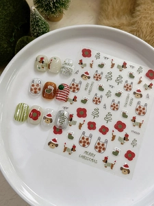 Close-up of Christmas nail art stickers with dog, tree, and flower patterns on white plate