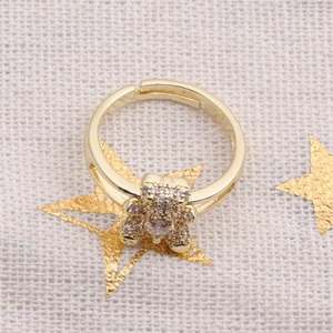 Detail of a gold adjustable bear ring with sparkling crystals on a textured background