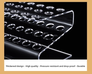 Close-up of clear acrylic multi-slot storage stand for pens and lipsticks on black background