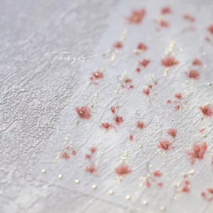 Macro shot of embossed pink floral nail stickers with gold accents and textured 3D details