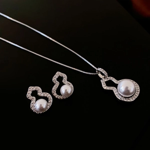 Macro shot of silver pearl gourd earrings and necklace set with zircon inlay