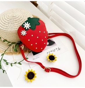 Close-up of red strawberry crossbody bag with green leaves and gold stud details