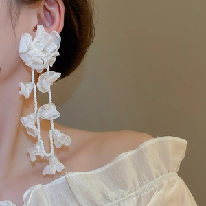 Detail of white chiffon flower earrings with long bead tassels on elegant model