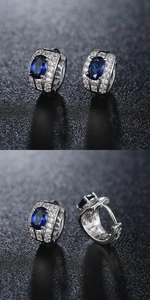 Detailed views of silver hoop earrings with a deep blue gemstone and white zircon pavé
