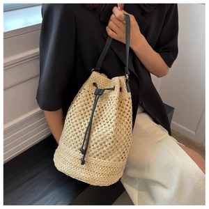 Detailed close-up of hollow straw bucket bag with black leather drawstring and strap