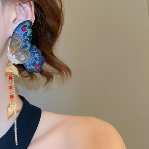 Détail macro de boucles d'oreilles papillon avec broderie fine et accents de perles