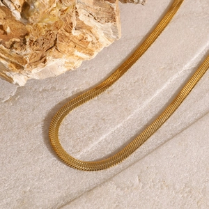 Detail shot of a minimalist gold triple-layered cross pendant necklace on a stone surface