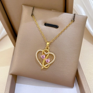 Detailed shot of golden heart pendant with pink gemstones and sparkling crystals in gift box