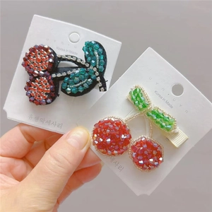 Close-up of handmade beaded cherry hair clips in red and green crystal beads