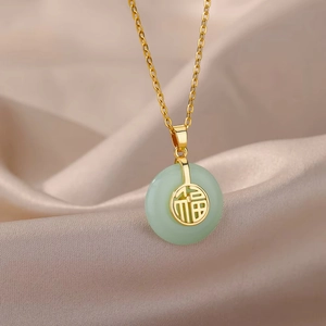 Golden four-leaf clover necklace with green jade-like Fu pendant on silk backdrop