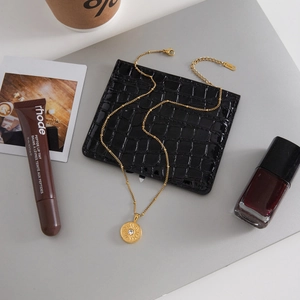 Detail of gold sun pendant necklace with zircon and steel tag on a lifestyle background