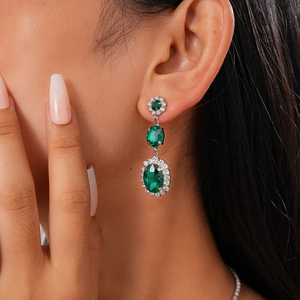 Macro shot of silver tiered emerald drop earrings with sparkling pavé crystal accents