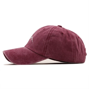 Détail de la broderie montagne blanche sur le côté d'une casquette bordeaux délavé