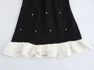 Détails du tissu texturé noir avec perles blanches et ourlet à volants superposés
