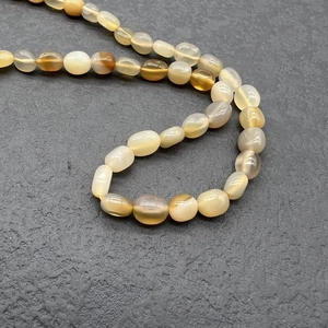 Detail of natural gemstone beads with smooth texture and warm amber tones on grey stone