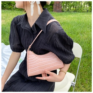 Detailed close-up of pink faux crocodile skin texture on a stylish underarm bag for women