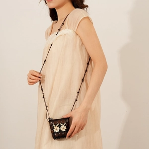 Détail d'un sac bandoulière en coque de coco fait main avec tissage floral et perles