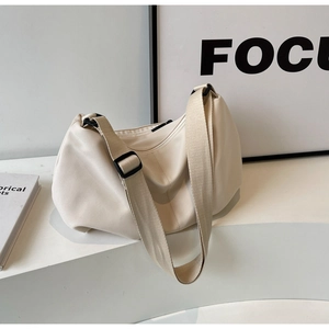 Close-up of a minimalist cream-white nylon crossbody tote bag with wide shoulder strap