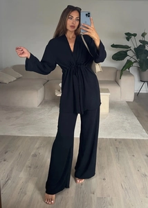 Detail of black V-neck long sleeve top with drawstring waist and matching wide leg pants
