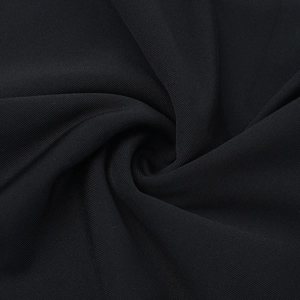 Gros plan du tissu en maille noire montrant la texture dense et l'éclat subtil de la robe