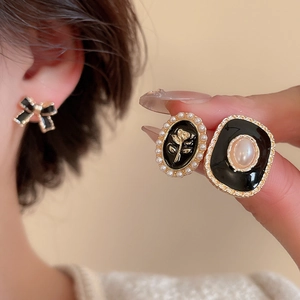 Détail de boucles d'oreilles vintage avec perles, nœud noir et gaufrage rose doré