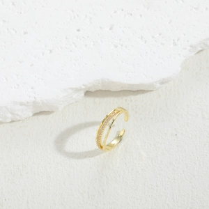 Detail of adjustable gold double-layer ring with sparkling zircon stones on textured stone