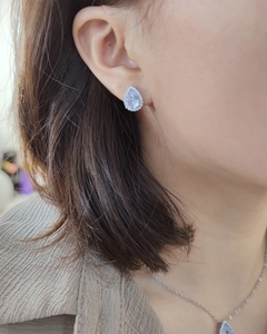 Close-up of silver teardrop zircon earrings and matching necklace worn by a model