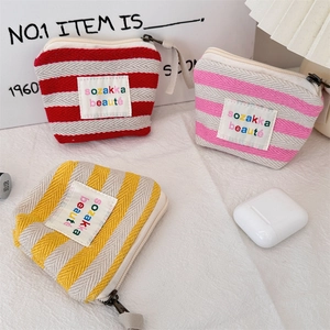 Macro detail of striped canvas makeup pouches with zip closure and fabric tags