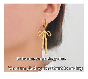 Close-up of vacuum plated gold bow earrings showing elegant streamline texture and finish
