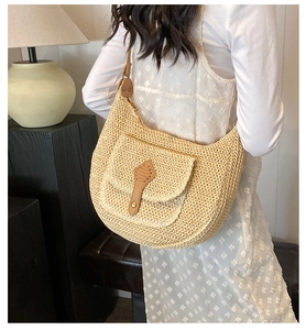 Detail of handwoven straw hobo bag featuring brown leather strap and decorative buckle