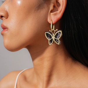 Close-up of butterfly hoop earring in dark purple acetate and gold finish on model