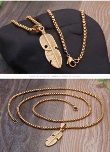 Macro shot of gold feather pendant with hollow texture on a box chain for men