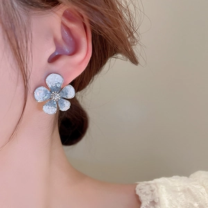 Detailed view of a light blue crystal flower earring with crystal center on a model