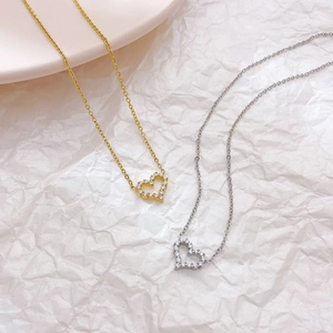 Elegant gold and silver heart-shaped necklaces with zircon inlays on white paper