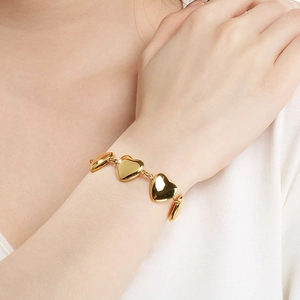 Bracelet cœur en acier inoxydable plaqué or 18 carats sur le poignet d'une femme