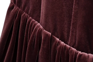 Close-up of pleated dark burgundy velvet fabric showing soft texture and fine stitching